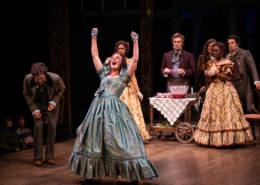 A woman raises her arms and shouts with joy in A Christmas Carol