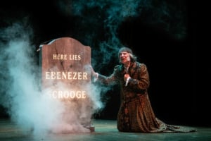 Scrooge kneels by his grave in A Christmas Carol