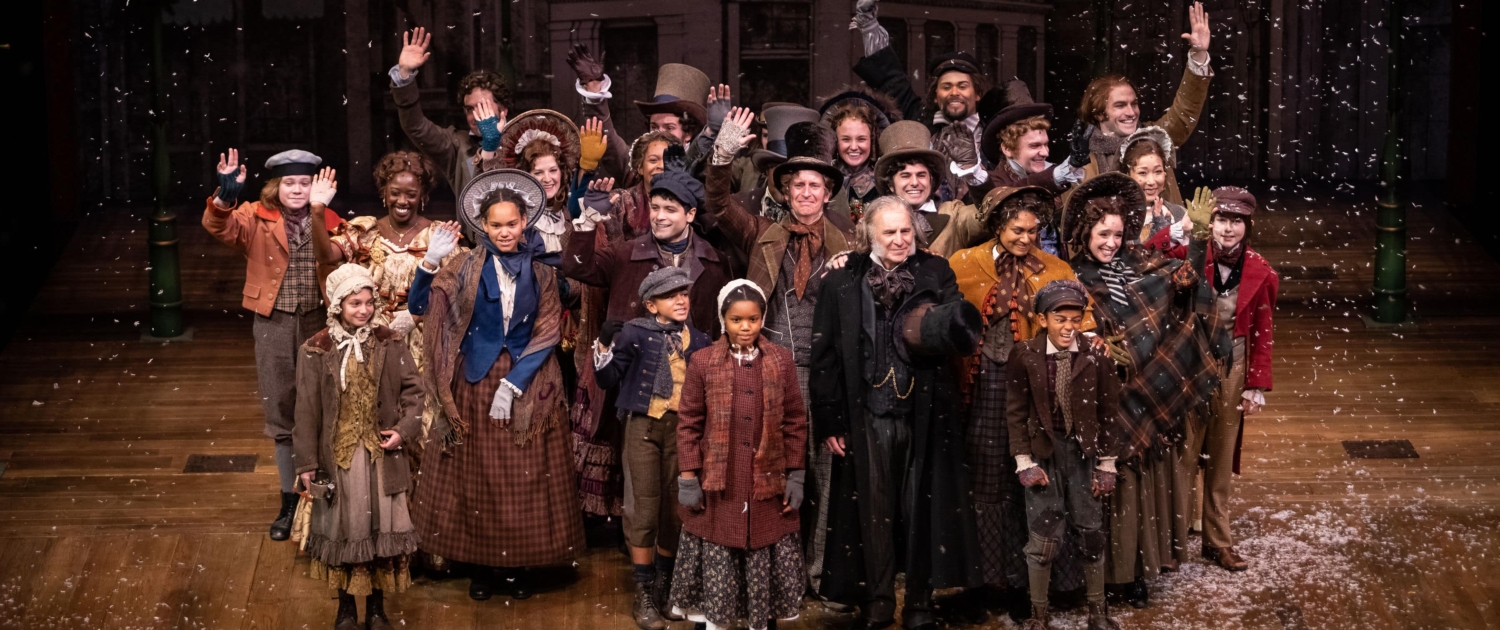 The cast of A Christmas Carol poses for a photo onstage