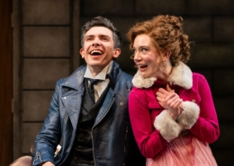 A man in a blue leather jacket laughs with a woman in a pink jacket.