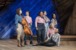 The cast of Rattlesnake Kate stands onstage with Neyla Pekarek carrying her cello as they sing
