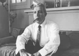 Black and white photo of a man in suit and tie smoking a cigar