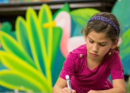 A young student in a DCPA Dramatic Learning workshop lays on the floor with a piece of paper