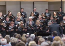 The Kantorei choir holds music books while singing onstage