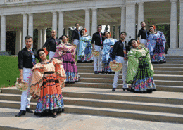 A group of dancers pose in colorful costumes