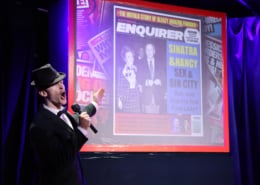 Cast member dressed as Frank Sinatra stands in front of a projected image of a gossip magazine cover