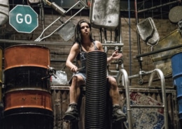 A woman performing in STOMP seated while drumming