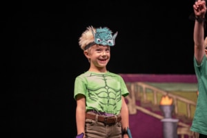 A child wearing a monster costume smiles onstage