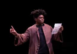 A DCPA education student reads from a piece of paper onstage