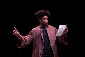 A DCPA education student reads from a piece of paper onstage