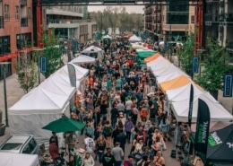 A large crowd of people walks through a market