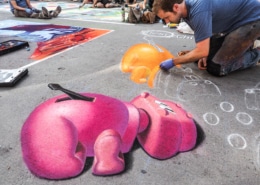 A man continues his chalk art of hungry hungry hippos