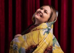 A woman smiles wrapped in a sunflower printed blanket