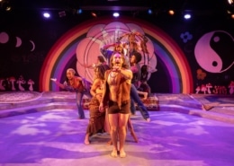 A group of hippies dance on a psychedelic stage