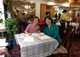 Two women are seated at a table and smile