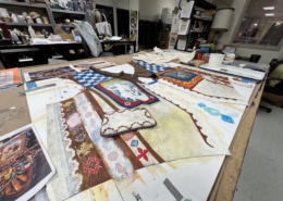 A hand-painted vest is laid out on a workstation