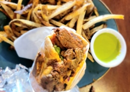 A close up of a gyro with fries