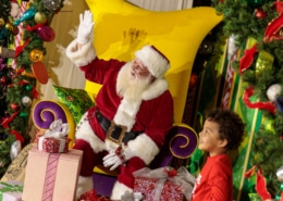 A child smiles with Santa surrounded by gifts