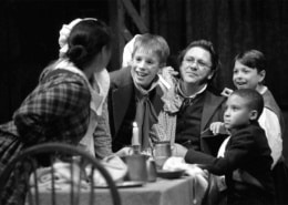 The Cratchit family crowds around a table in A Christmas Carol