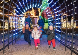 A group of children run through a lighted archway at Camp Christmas