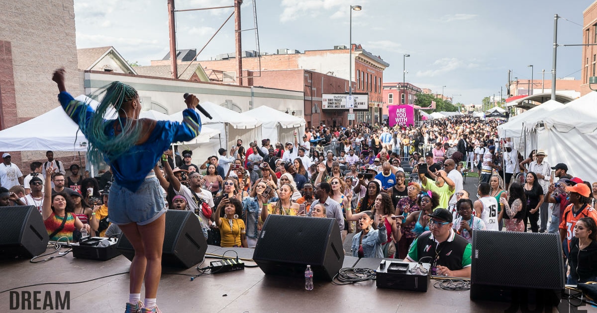 A woman performs in front of a large crowd at Juneteenth Music Festival