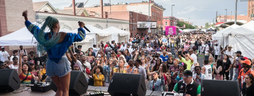 A woman performs in front of a large crowd at Juneteenth Music Festival