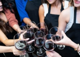Women toast with wine glasses at a painting class