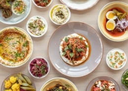 Several plates filled with Mediterranean food on a table at Safta