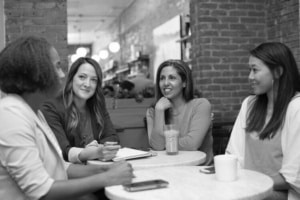 A group of women are seated at a table in discussion