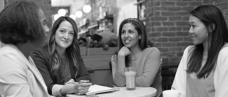 A group of women are seated at a table in discussion