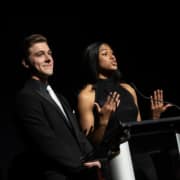 Thomas Beeker and Madison Manning, wearing black tie, present at a podium during the 2023 Bobby G Awards