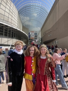 Three students dressed in costume pose for a photo in the Arts Complex during the DPS Shakespeare Festival