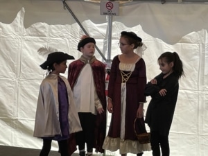 A group of students wearing Elizabethan style costumes perform during the DPS Shakespeare Festival