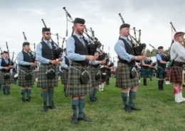 Rows of musicians playing the bagpipes wearing kilts