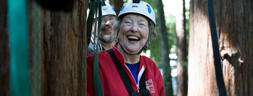 A woman on a zip line in the woods laughing