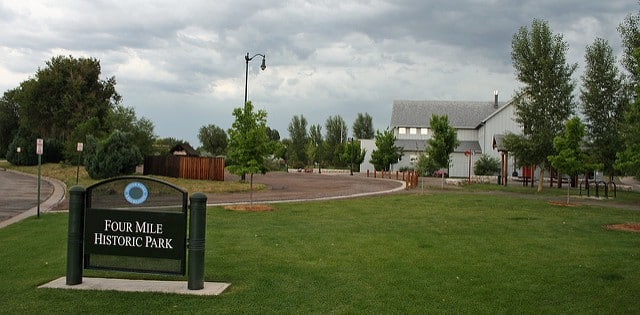 The sign for Four Mile Historic Park in the foreground with green space and a house behind
