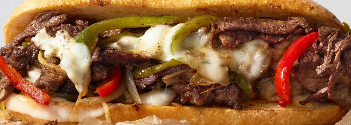 A melty cheesesteak with provolone, peppers, and meat