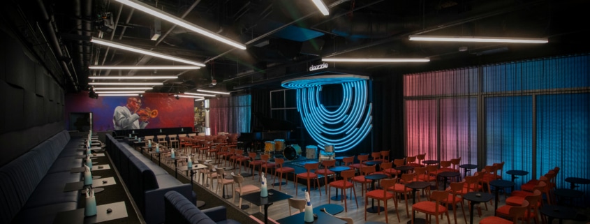 The main listening room at Dazzle's new location. Many red chairs circle a small stage for a jazz band.