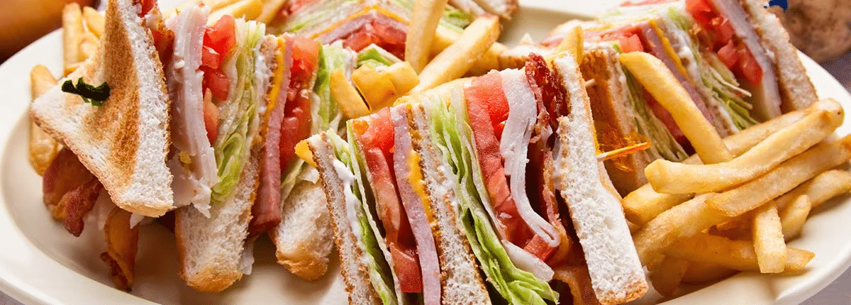 A triangularly sliced club sandwich on a large plate with french fries