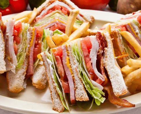 A triangularly sliced club sandwich on a large plate with french fries