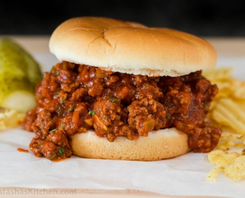 An overflowing sloppy joe sandwich on a simple white hamburger bun.