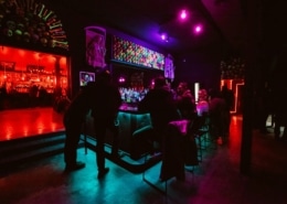 Interior of The Crypt. People are sitting at a neon bar