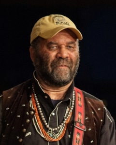 A headshot of Otis Taylor. He's wearing dark clothing and a baseball cap.