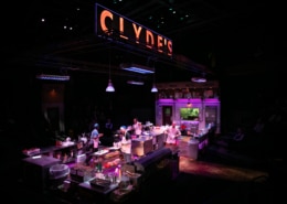 Clyde's glows in large lettering above the kitchen set. Four cooks are scattered about, prepping the kitchen.