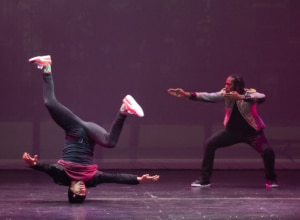 One dancer on the left spins on his head, the other on the right points and poses