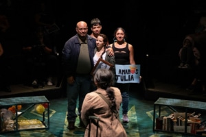 A teenage girl in a brown plaid blazer looks at her family as they bid her farewell.