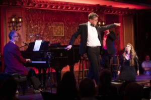 A man strikes a pose onstage, pointing to the audience