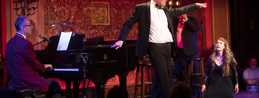 A man strikes a pose onstage, pointing to the audience
