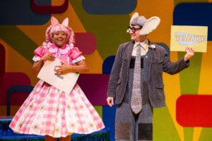 Piggie grins at the audience clutching an envelope addressed to her. Gerald the Elephant grins at Piggie and holds up a card that reads PARTY!