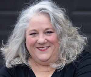 Denver actress Leslie O'Carroll with shoulder-length wavy gray hair, wearing a black top.